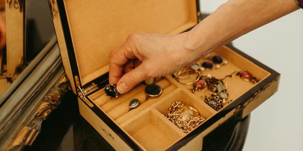 A person putting away their jewelry in a jewelry box.