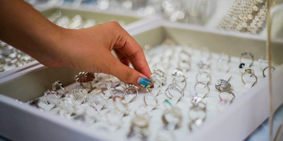 A display of various rings, and a person's hand reaching out to a ring.